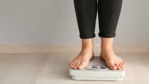 Woman Standing on Scales. Weight Loss Concept